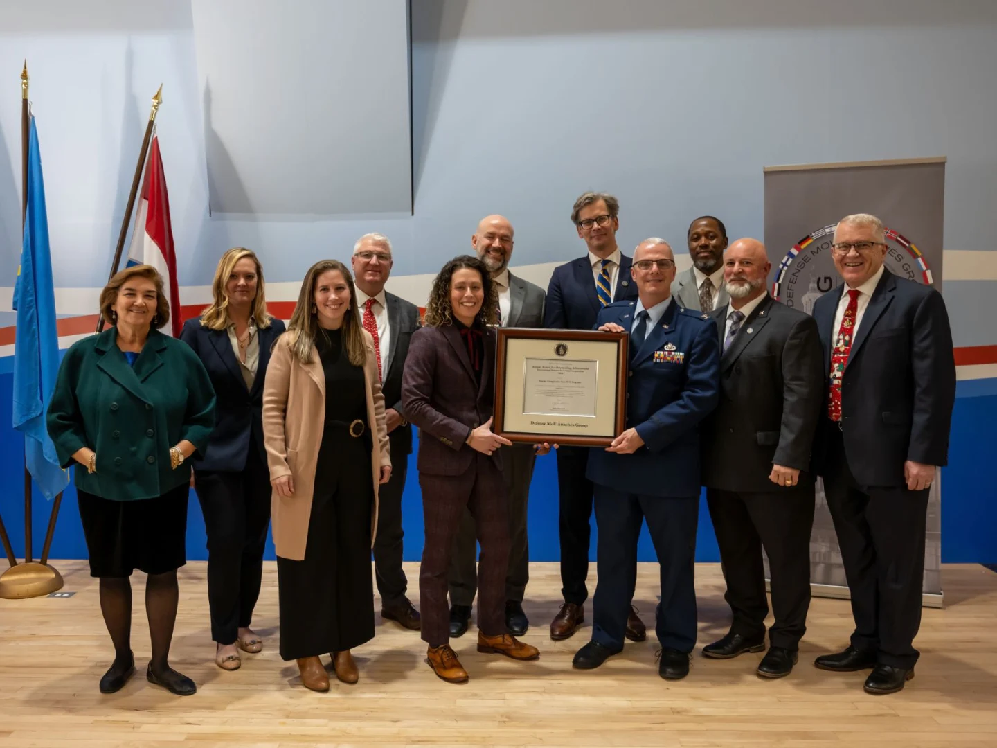 Group holding framed certificate at formal ceremony