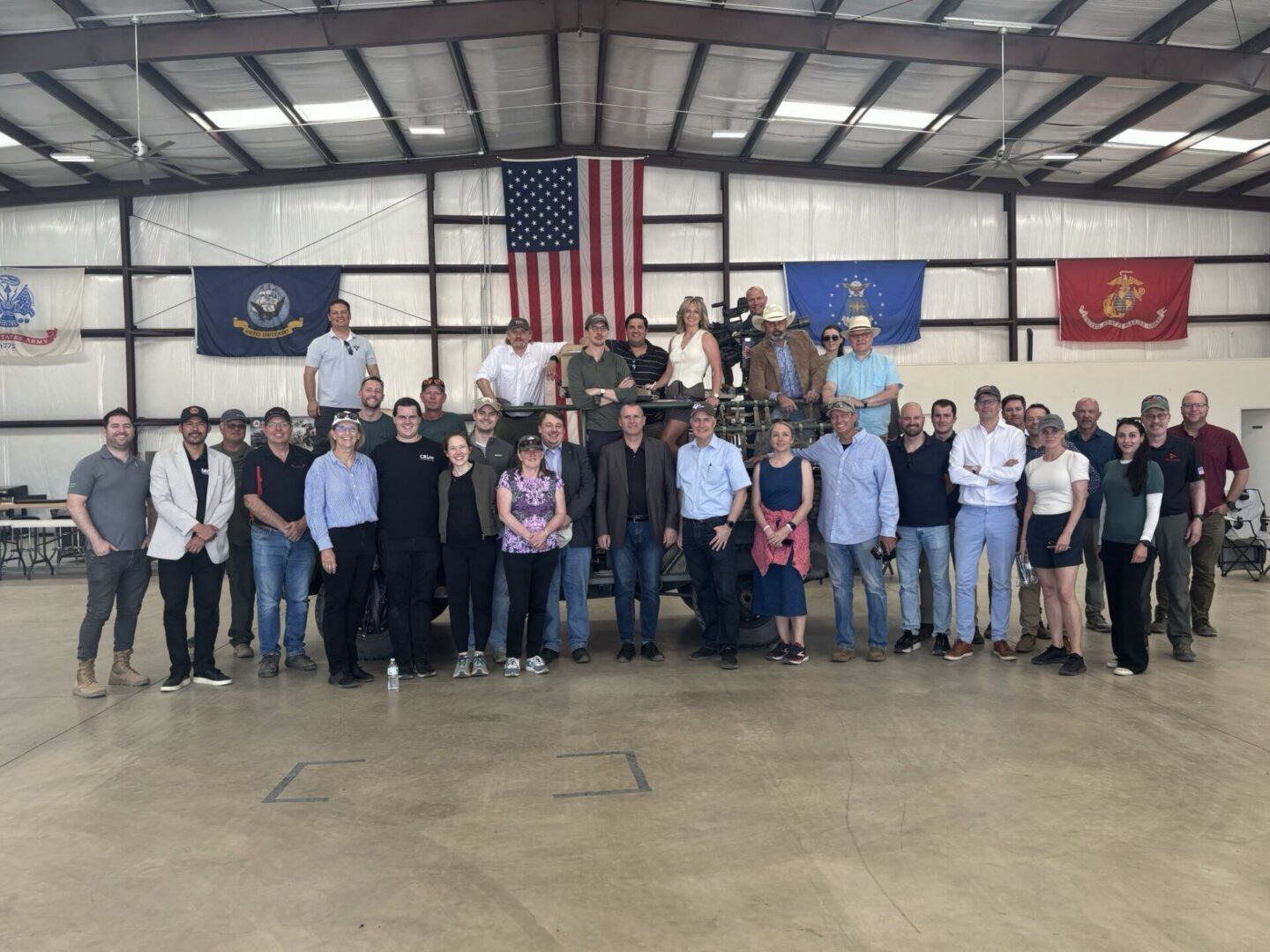 Large group posing in hangar with flags