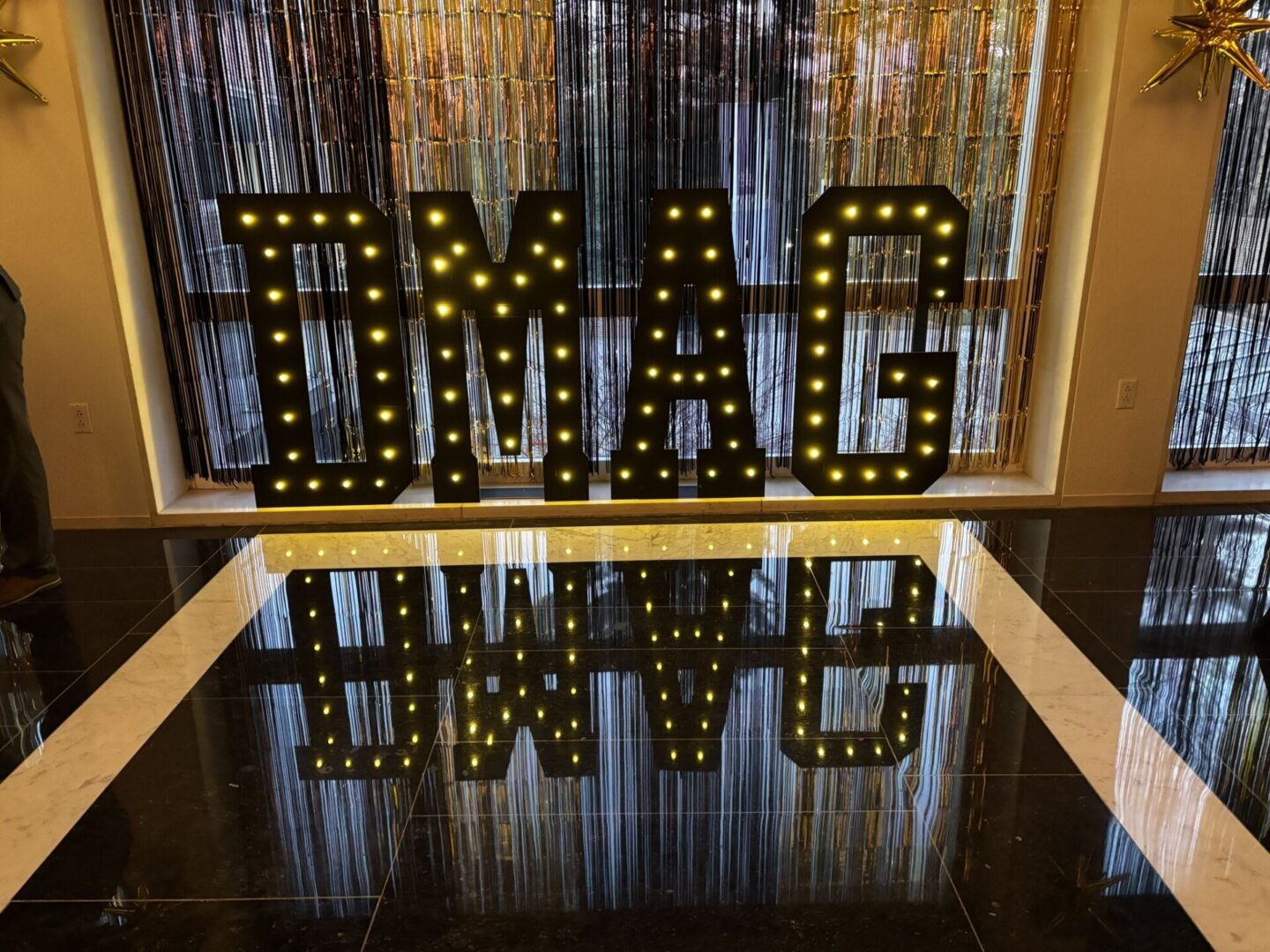 Illuminated TMAC marquee letters reflected on floor